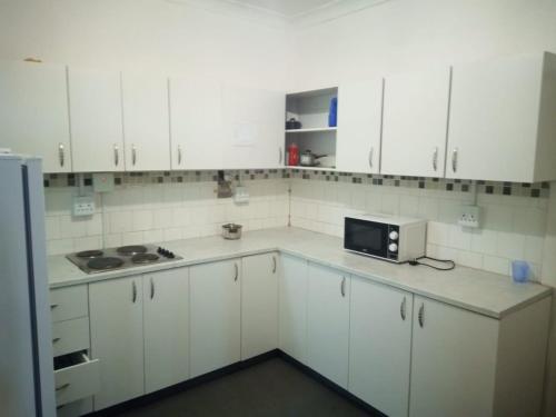 a white kitchen with white cabinets and a microwave at 18 on Shores in Pietermaritzburg