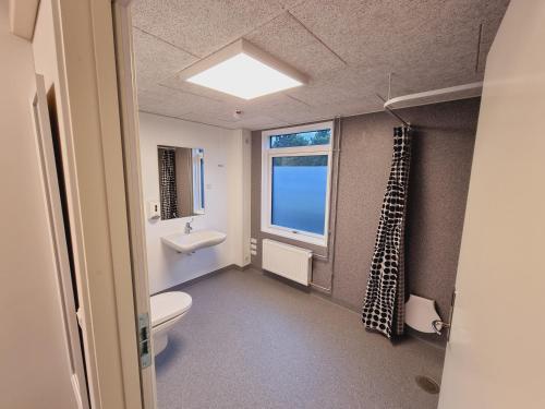 a bathroom with a toilet and a sink and a window at Stop'n Sleep Hotel in Rødby