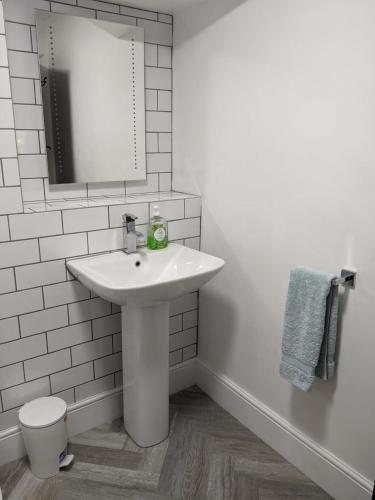 a white bathroom with a sink and a mirror at Granary Cottage in Mickleton