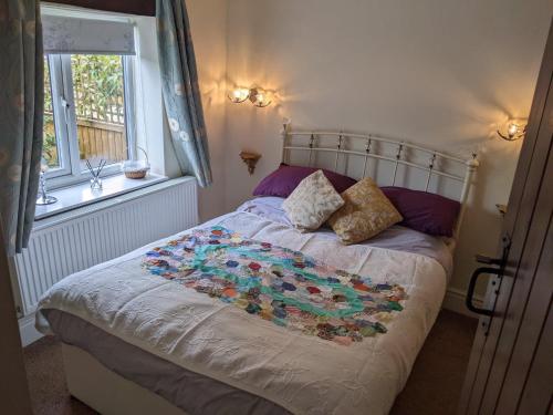 a bedroom with a bed with a flower quilt on it at Granary Cottage in Mickleton