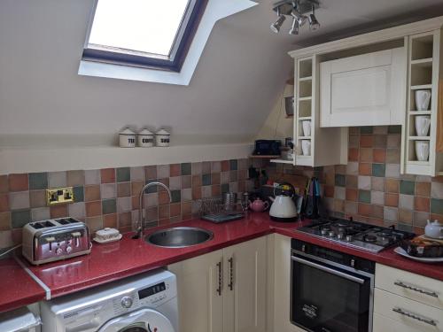 a kitchen with a sink and red counter top at Granary Cottage in Mickleton