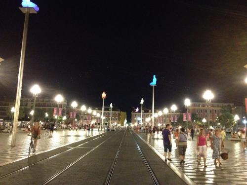 a group of people walking on a street at night at Hôtel du Petit Louvre in Nice