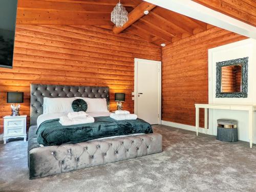 a bedroom with a bed and a wooden wall at Kaoglen-Blossom-Hot tub-Cairngorms-Pet Friendly in Balnald