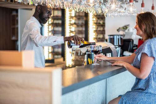 a man pouring a woman a glass of wine at a bar at ibis Lyon Sud Oullins in Oullins