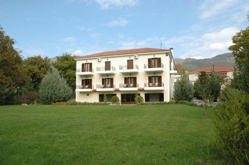 a large white building with a large grass field at Aroanios Hotel in Klitoria