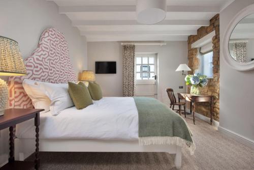 a bedroom with a large white bed and a table at Nevill Arms Inn in Medbourne