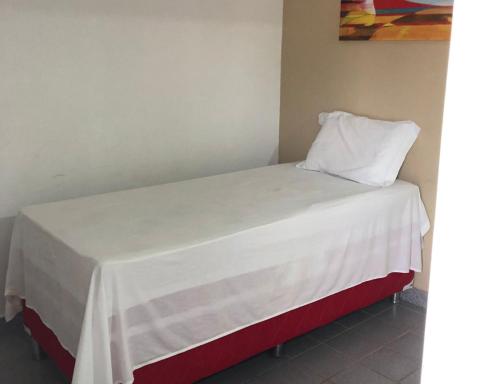 a bed with a white blanket and a pillow on it at Pousada Villa Goyá in São José da Coroa Grande