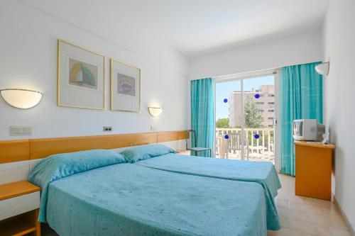 a bedroom with a blue bed and a window at O7 Club Cala Ratjada in Cala Ratjada