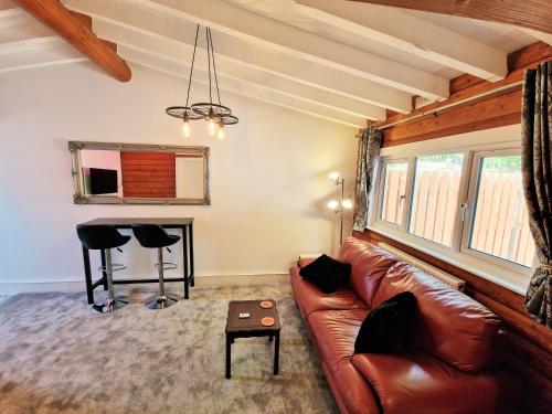 ein Wohnzimmer mit einem Ledersofa und einem Tisch in der Unterkunft kaoglen Wild-Hot tub-Cairngorms-Pet Friendly in Balnald