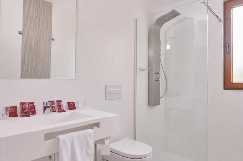 a white bathroom with a toilet and a shower at Posada Naturae in Cabarceno