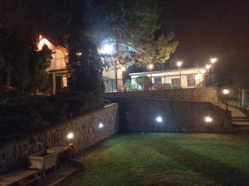 a yard with a wall and a house at night at Beautiful holiday house in Sremska Kamenica