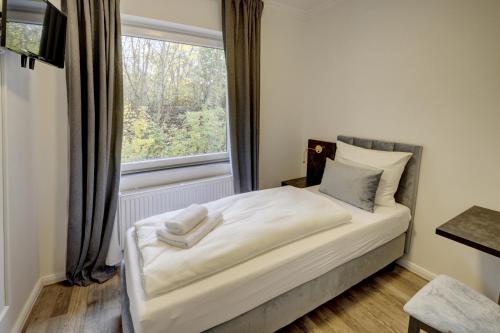 a small bedroom with a bed with a window at Pension Hygge am Hafen in Flensburg