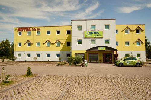 einem grünen Auto, das vor einem Gebäude parkt in der Unterkunft Hotel City Inn in Magdeburg