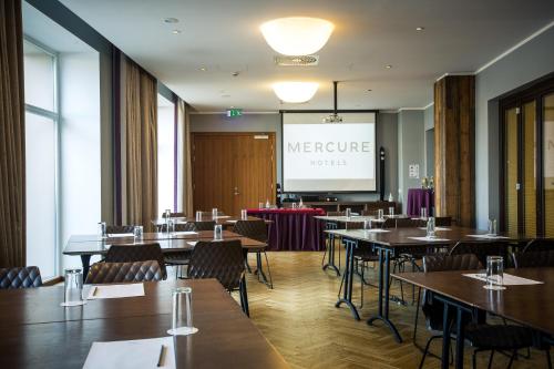 a conference room with tables and chairs and a screen at Mercure Riga Centre in Rīga
