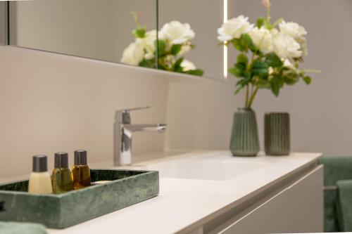 a bathroom counter with a sink with a vase of flowers at GRÜN & URBAN - direkt an der Therme - 15 Minuten ins Zentrum in Vienna