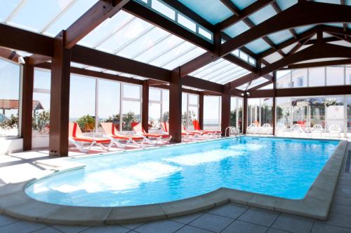 a swimming pool with lounge chairs and a large building at Hotel Les Dunes in La Tranche-sur-Mer