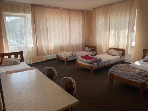a room with three beds and a table and chairs at Pasile in Kaunas