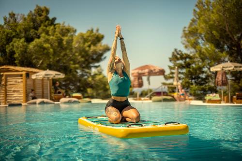 a woman is on a paddle board in a pool at PLACES Dalmacija by Valamar in Makarska
