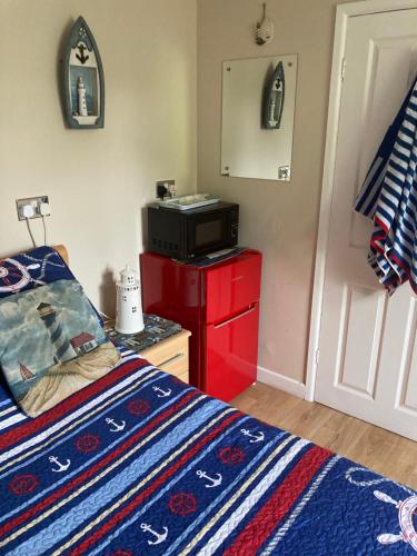 1 dormitorio con cama y tocador rojo con TV en Cove Cott en Warsash
