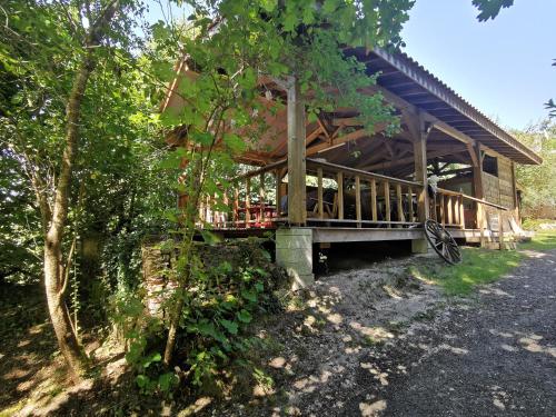 a wooden house with a porch in the woods at Le Tipi Ethnique au bord de la rivière in Mios