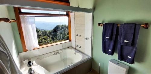 a bathroom with a bath tub and a window at Hospedaria Aikó in São Bento do Sapucaí