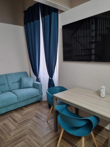 a living room with a blue couch and a table and chairs at Palazzo Sarti Suites in Rodi Garganico