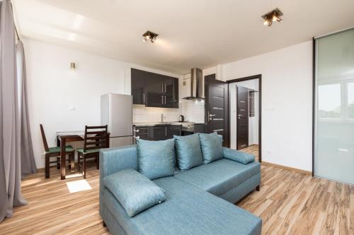 ein Wohnzimmer mit einem blauen Sofa und einer Küche in der Unterkunft Podchorążych 41 by Homeprime in Warschau