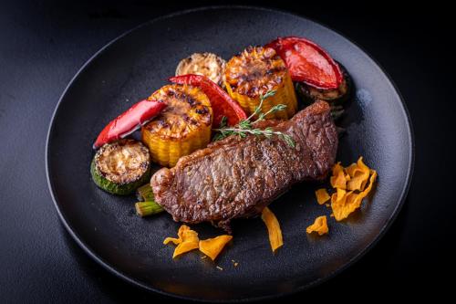 a black plate of food with meat and vegetables at Mercure Riga Centre in Rīga