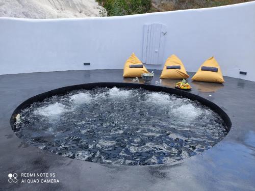 a large pool of water with yellow cushions in at Thea Luxury Resort in Fira