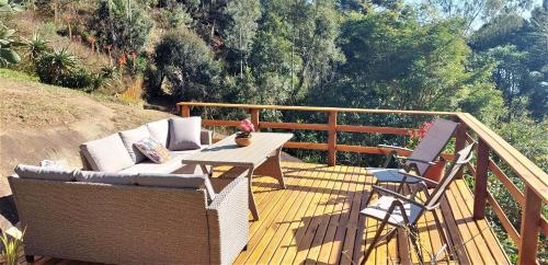 a deck with a couch and a table and chairs at Hospedaria Aikó in São Bento do Sapucaí