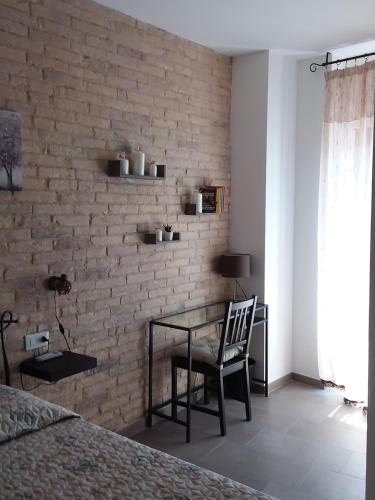 a bedroom with a table and a brick wall at Primae Noctis Rooms in Apartments in Roccascalegna
