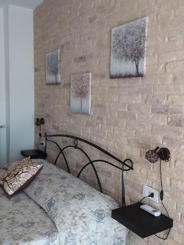 - une chambre avec un lit et un mur en briques dans l'établissement Primae Noctis Rooms in Apartments, à Roccascalegna