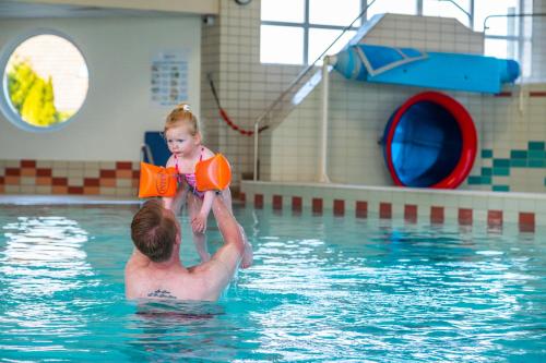 a man holding a little girl in a swimming pool at Europarcs Ijsselmeer in Medemblik