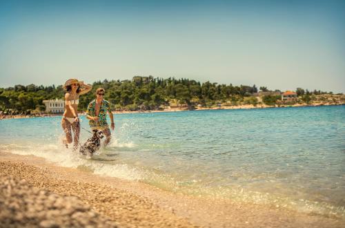 two people walking in the water on the beach at PLACES Dalmacija by Valamar in Makarska