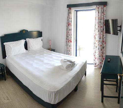 sypialnia z dużym białym łóżkiem i oknem w obiekcie Helen's appartments w mieście Galaxidi