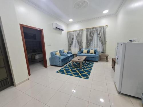 a living room with two blue couches and a refrigerator at الزمرد للشقق المخدومة in Al Khobar