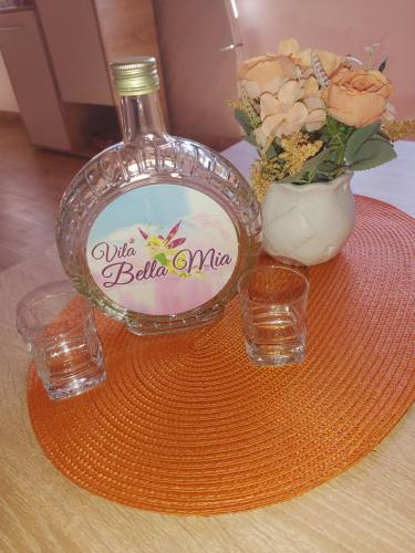 a bottle of wine and two glasses and a vase with flowers at Vila Bella Mia in Timotijevići