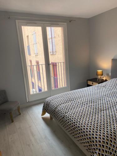 a bedroom with a bed and a large window at Superbe appartement climatisé avec parking privé in Port-Vendres