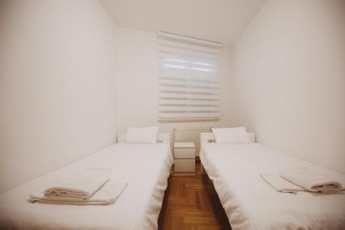 two beds in a white room with a window at Apartman 4, Sinđelićeva 40 in Gornji Milanovac