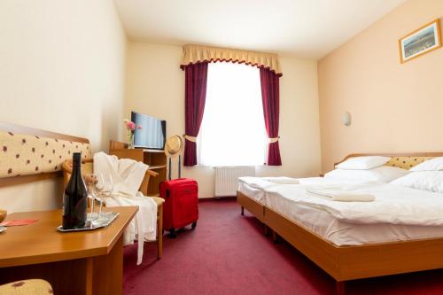 a hotel room with two beds and a desk at Hotel Imperial Gyogyszallo es Gyogyfurdo in Kiskőrös