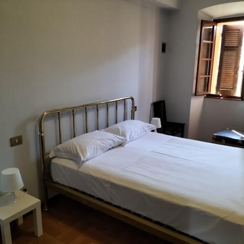 a bedroom with a bed with white sheets and a window at Casa Rina in Nesso
