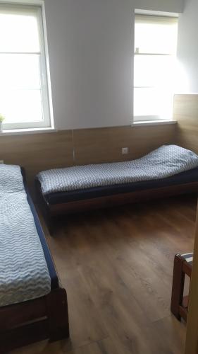 two beds in a room with two windows at Pokoje Gościnne z łazienkami przy Wrocławiu, darmowy parking in Długołęka