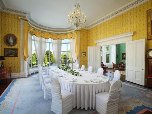 a large dining room with a long table and white chairs at Lyrath Estate in Kilkenny