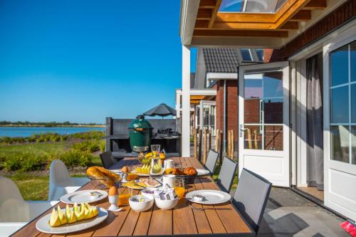 a wooden table with food on a balcony with the ocean at Europarcs Ijsselmeer in Medemblik