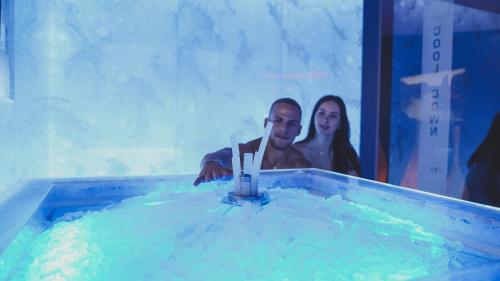 a man and a woman standing in a swimming pool at Hotel Gut Brandlhof in Saalfelden am Steinernen Meer