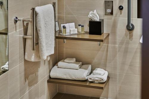 a bathroom with towels on shelves in a bathroom at Genting Hotel & Spa at Resorts World Birmingham in Bickenhill