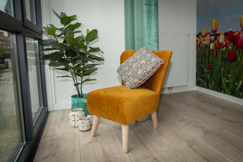 a yellow chair with a pillow on it with a plant at Bed & Breakfast Bakker Meijer in Heemskerk