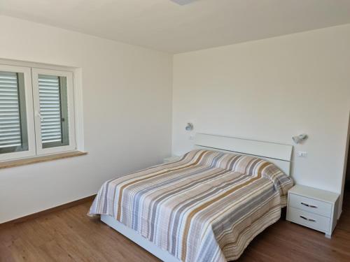 a white bedroom with a bed and a window at Villa Epi in Sperlonga