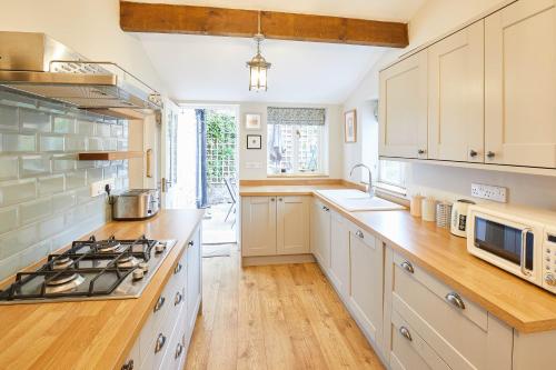 a kitchen with white cabinets and a stove top oven at Host & Stay - Sixpence Cottage in Pickering
