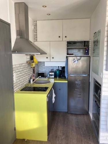 La cuisine est équipée d'un comptoir jaune et d'un réfrigérateur. dans l'établissement T2 Cabourg - Résidence Le Sporting, à Cabourg
